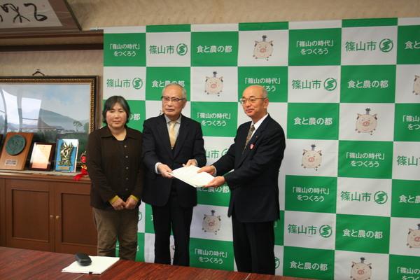 市長と食育推進計画策定委員会の方が食育推進計画の書類を持ち、その横にいる女性と一緒に記念撮影している写真